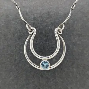 Hand-engraved sterling silver horseshoe necklace featuring a blue topaz gemstone by Modern Heirloom® Studio.
