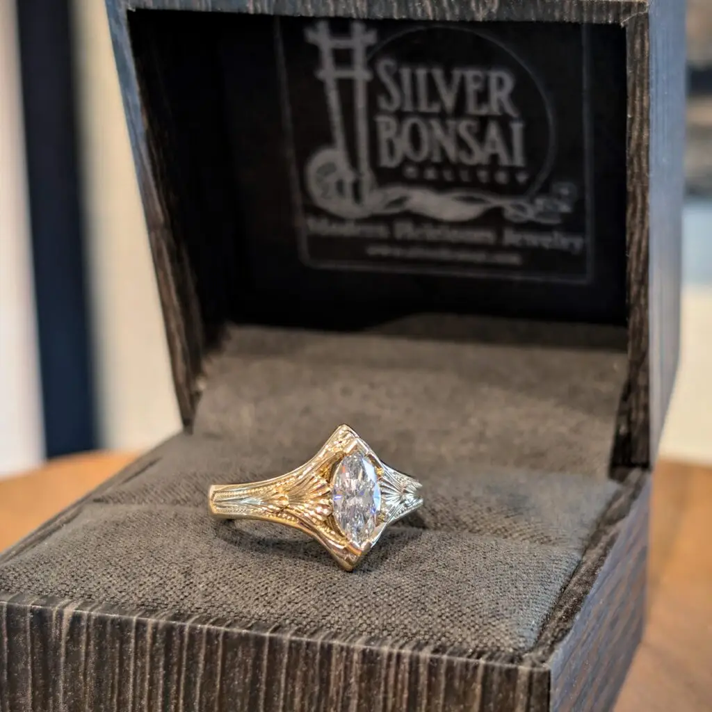 Close-up of a faceted diamond ring set in a gold band, resting on black velvet inside an open jewelry box