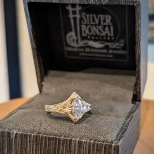 Close-up of a faceted diamond ring set in a gold band, resting on black velvet inside an open jewelry box